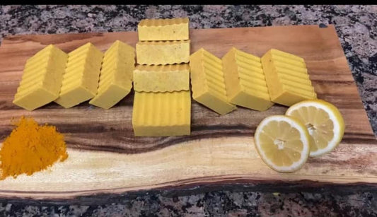 Yellow soap bars on a wooden cutting board with lemon slices and turmeric powder.