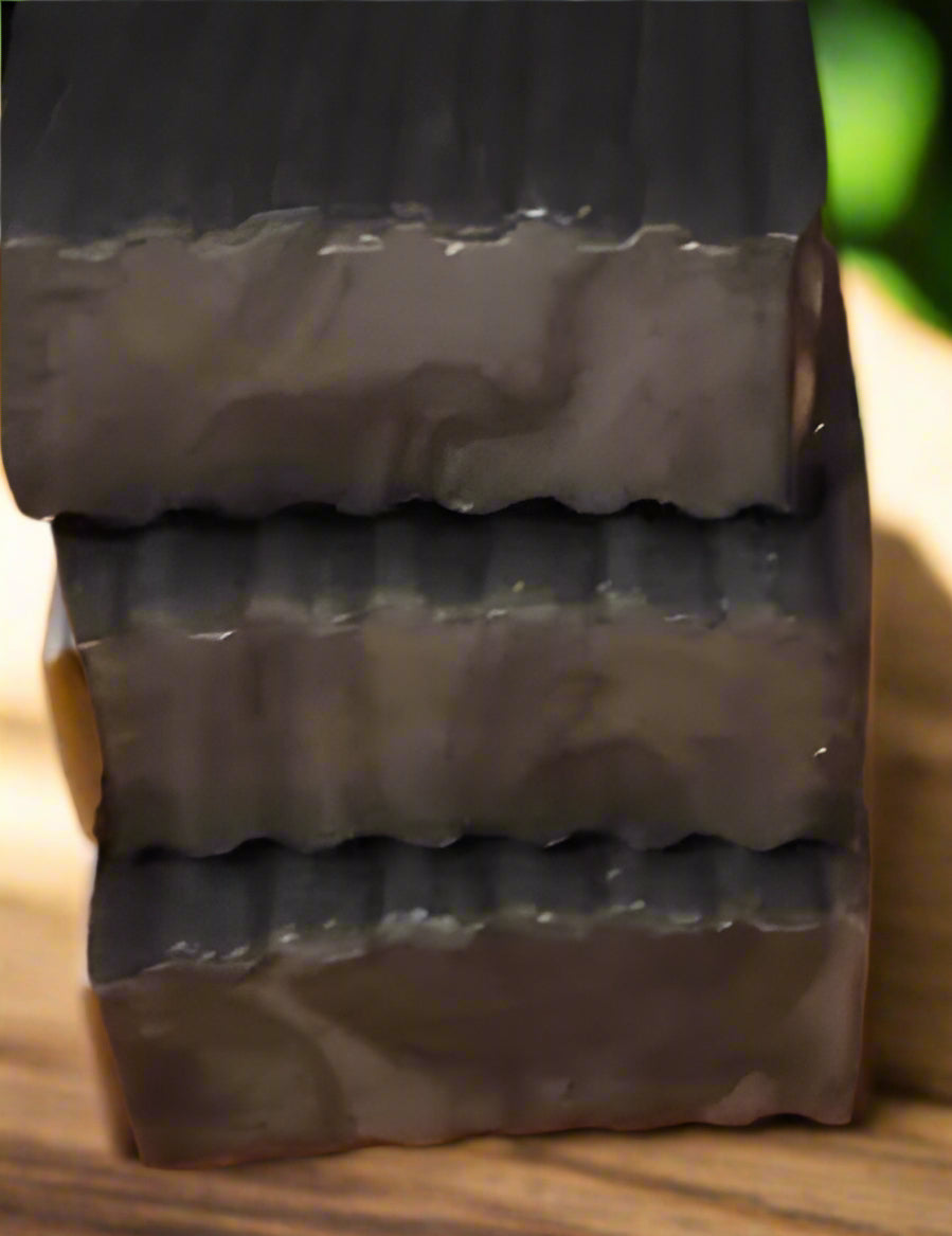 Stack of activated coconut charcoal soap bars on a wooden surface